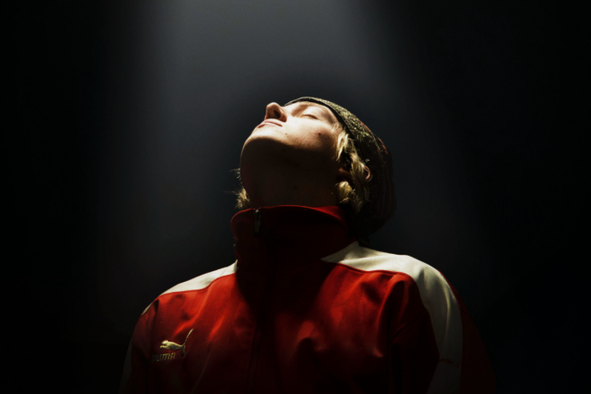 Person looking skyward in the dark with a light shining on them from above